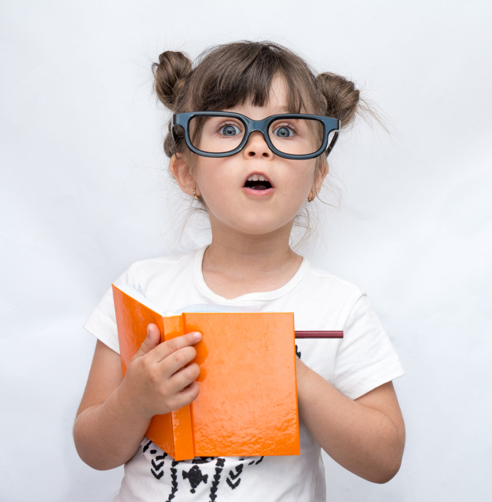 Surprised,Cute,Child,In,Eyeglasses,,Writing,In,Notebook,Using,Pencil,
