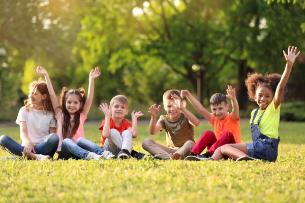 Cute,Little,Children,Sitting,On,Grass,Outdoors,On,Sunny,Day